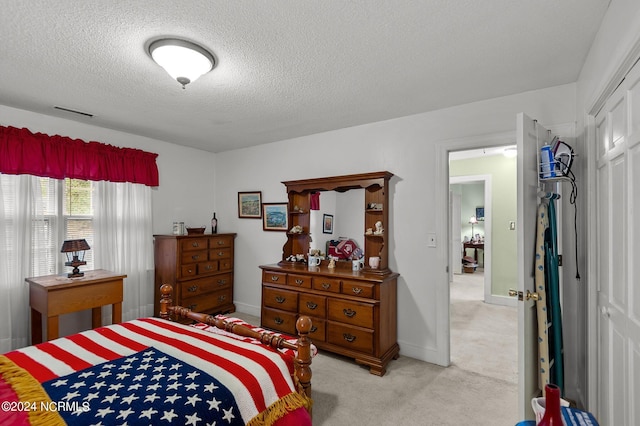 bedroom featuring a textured ceiling and light carpet