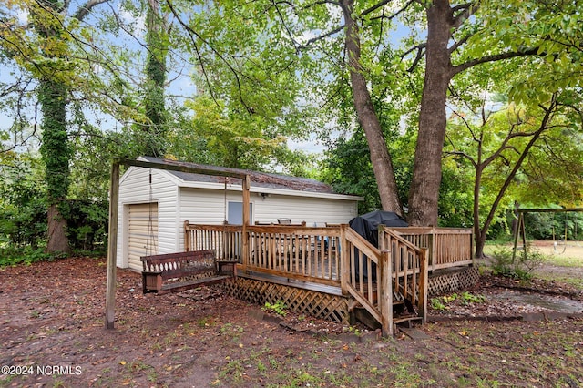 back of house featuring an outdoor structure, a garage, and a wooden deck