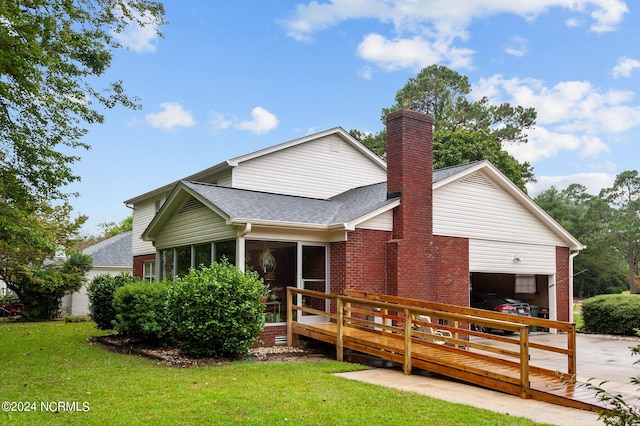 rear view of house with a garage, a sunroom, and a lawn