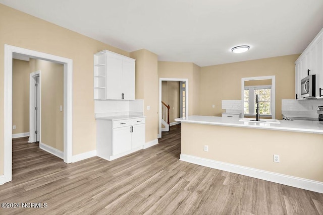 5104 Boss Ct SE, Southport, NC 28461 - kitchen featuring stainless steel microwave, a sink, light wood-style floors, and white cabinets