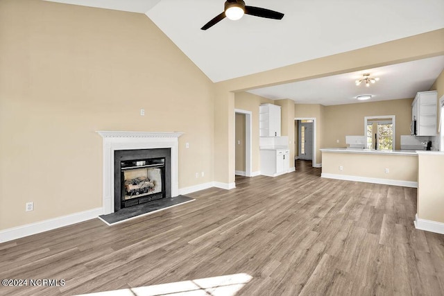 5104 Boss Ct SE, Southport, NC 28461 - unfurnished living room featuring ceiling fan, light wood-style flooring, a fireplace, high vaulted ceiling, and baseboards