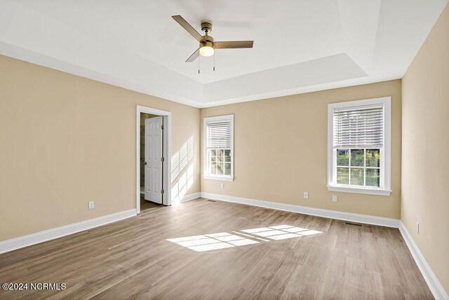 5104 Boss Ct SE, Southport, NC 28461 - spare room featuring a tray ceiling, wood finished floors, baseboards, and ceiling fan