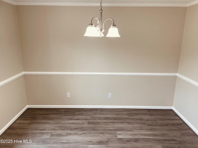 empty room featuring dark wood-type flooring, crown molding, and a chandelier