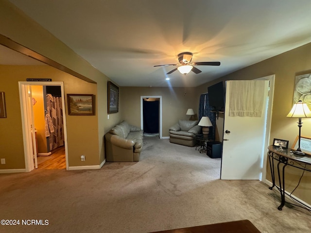 interior space featuring light colored carpet, ceiling fan, a walk in closet, and ensuite bath