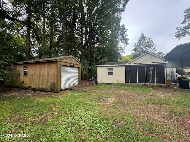 view of yard with a sunroom, an outdoor structure, and a garage