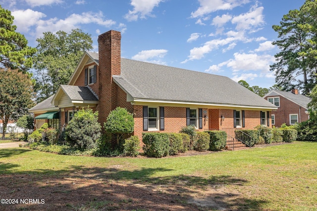 view of front of property with brick siding, a chimney, a front lawn, and roof with shingles