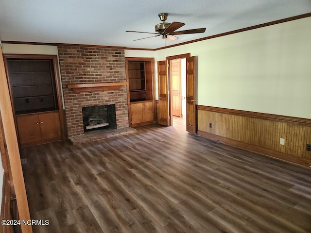 unfurnished living room with dark wood-type flooring, wood walls, a fireplace, and ceiling fan