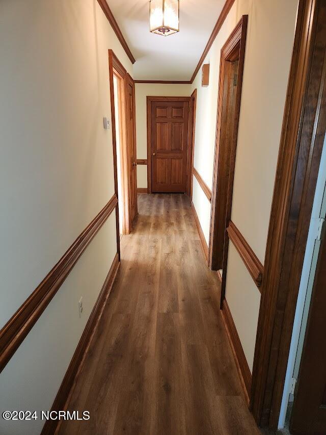 hallway featuring crown molding and dark hardwood / wood-style flooring