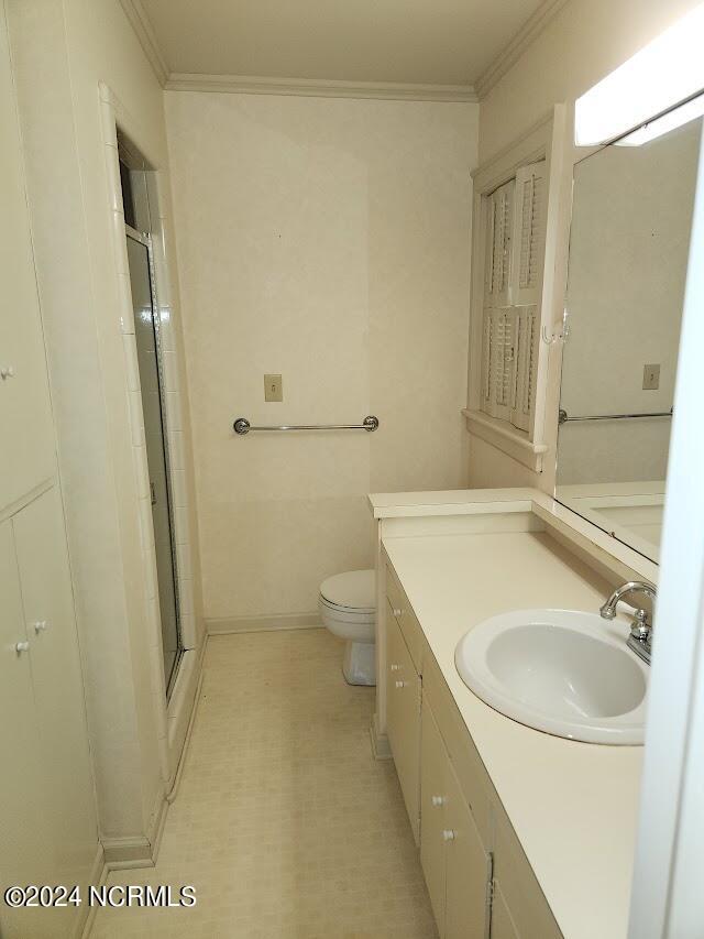 bathroom featuring crown molding, toilet, a shower with door, and vanity