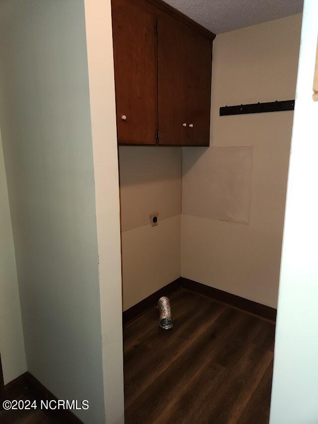 washroom with electric dryer hookup, dark hardwood / wood-style flooring, a textured ceiling, and cabinets