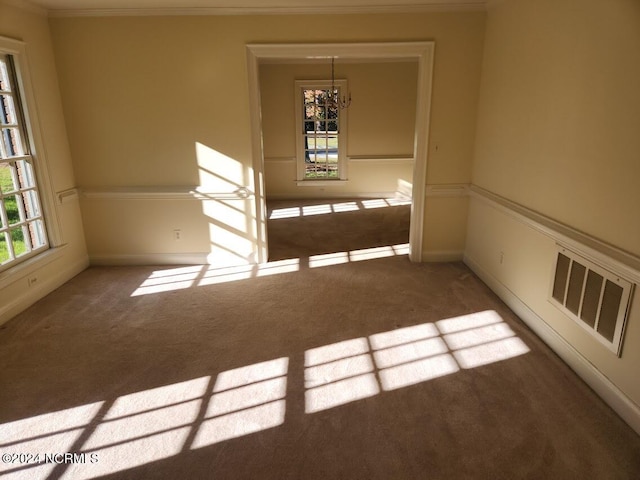 empty room with crown molding, carpet floors, and a chandelier