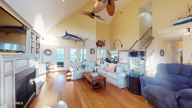 living room featuring light hardwood / wood-style flooring, high vaulted ceiling, a fireplace, and ceiling fan