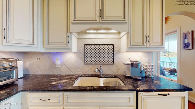 kitchen featuring dark stone countertops, decorative backsplash, and sink