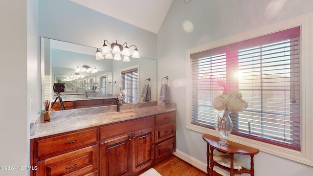 bathroom with vaulted ceiling, wood finished floors, vanity, and baseboards