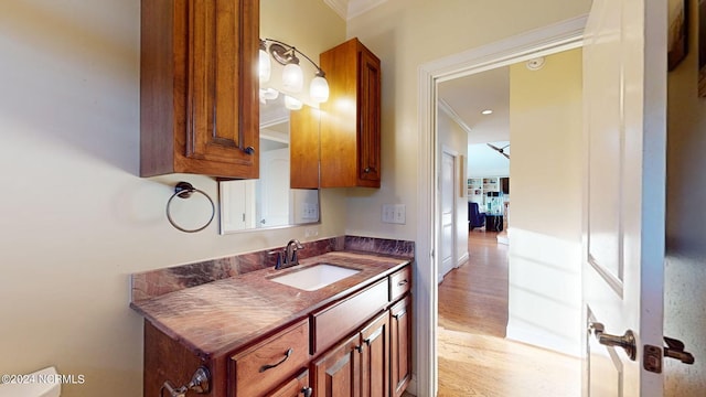 bathroom featuring hardwood / wood-style flooring, crown molding, and vanity