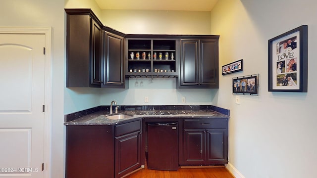 bar featuring dark stone countertops, hardwood / wood-style flooring, and sink