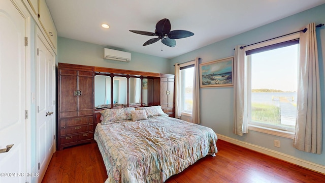 bedroom with wood finished floors, multiple windows, baseboards, and a wall mounted AC