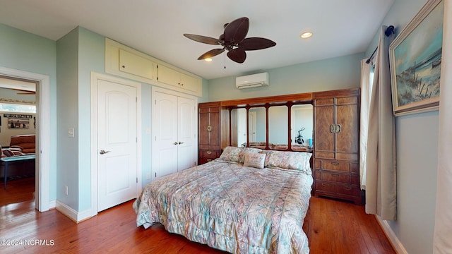 bedroom with a closet, wood finished floors, baseboards, and a wall mounted AC