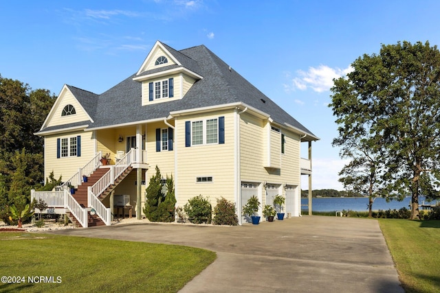 view of front facade with a garage, a shingled roof, a water view, driveway, and stairway