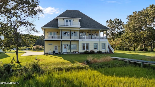 rear view of house featuring a balcony and a lawn