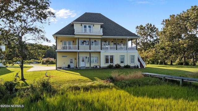 rear view of property with a balcony and a yard