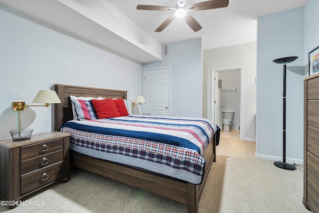 bedroom with light carpet, ensuite bath, and ceiling fan