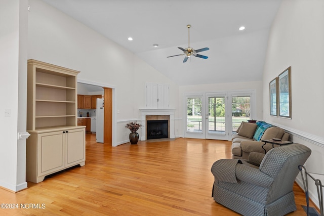 living room with a fireplace, high vaulted ceiling, ceiling fan, and light hardwood / wood-style floors