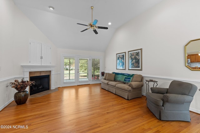 living room with high vaulted ceiling, light hardwood / wood-style flooring, ceiling fan, and a tile fireplace