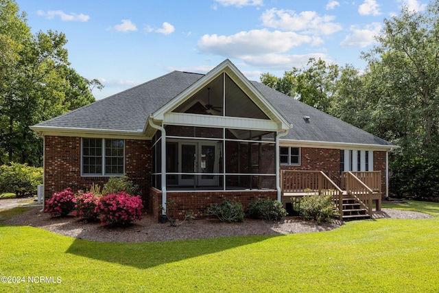 rear view of house featuring a yard, a sunroom, and a deck