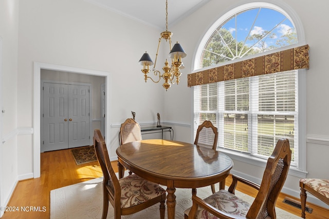 dining space with a wealth of natural light, ornamental molding, a chandelier, and light hardwood / wood-style flooring