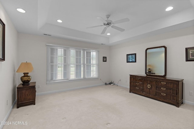 bedroom featuring ceiling fan, a raised ceiling, and light carpet