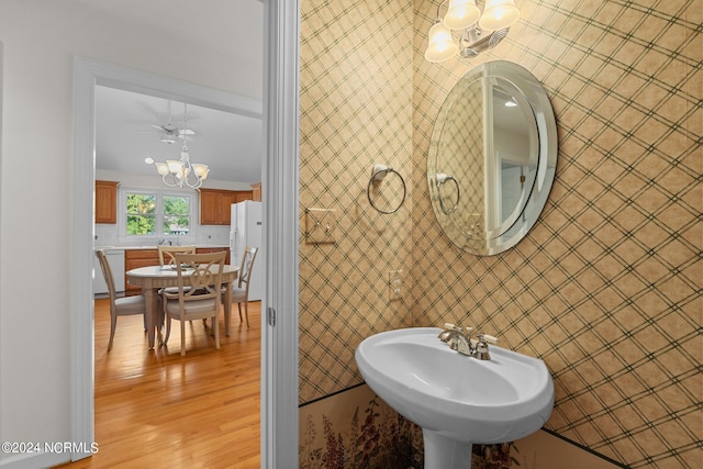 bathroom with hardwood / wood-style floors, a chandelier, crown molding, and sink