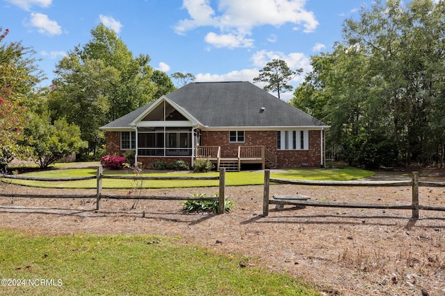 back of property featuring a lawn, a sunroom, and a deck