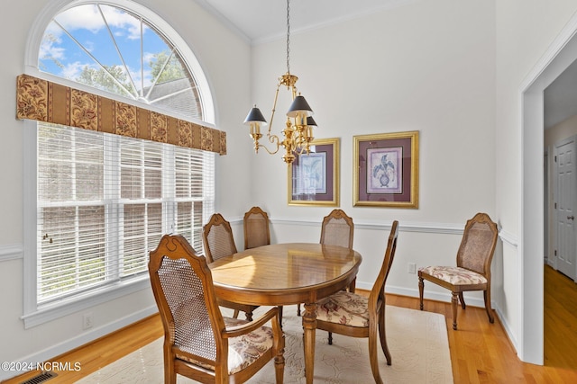 dining area featuring crown molding, a chandelier, and light hardwood / wood-style floors