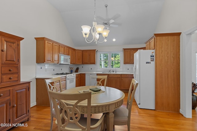 kitchen with light wood-type flooring, ceiling fan with notable chandelier, white appliances, and high vaulted ceiling