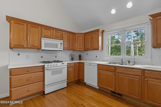 kitchen featuring white appliances, sink, decorative backsplash, lofted ceiling, and light wood-type flooring