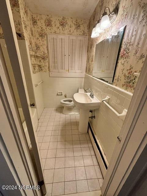 bathroom with tile walls, a baseboard heating unit, and tile patterned floors