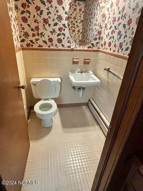 bathroom with tile walls, toilet, sink, tile patterned floors, and a baseboard heating unit