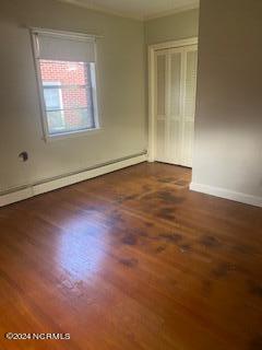 empty room with a baseboard heating unit and wood-type flooring