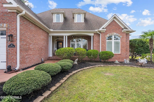 view of front of property featuring a garage, a porch, and a front yard