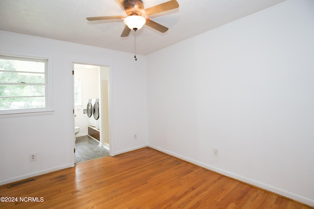 empty room with light wood-type flooring, washing machine and clothes dryer, and ceiling fan