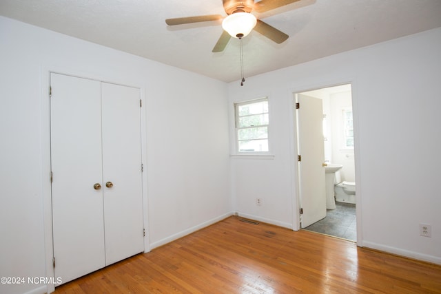 unfurnished bedroom with ceiling fan, a closet, ensuite bathroom, and light hardwood / wood-style floors