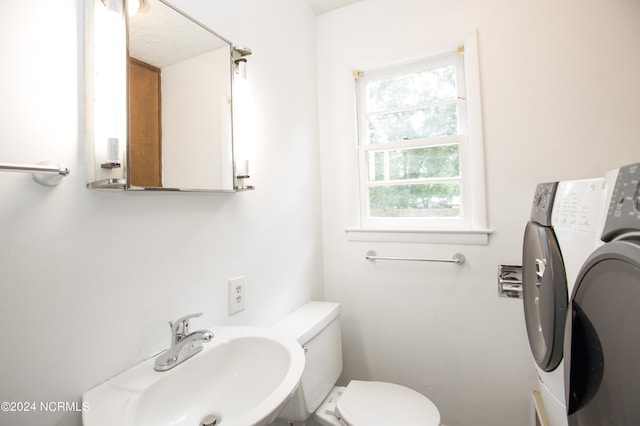 bathroom with washer / dryer, toilet, a wealth of natural light, and sink