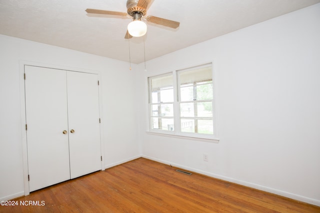 unfurnished bedroom featuring ceiling fan, a closet, and hardwood / wood-style flooring