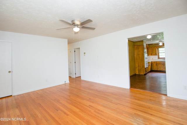 unfurnished room featuring a textured ceiling, ceiling fan, and light wood-type flooring