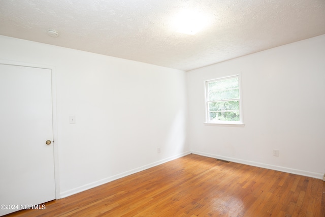 spare room with wood-type flooring and a textured ceiling