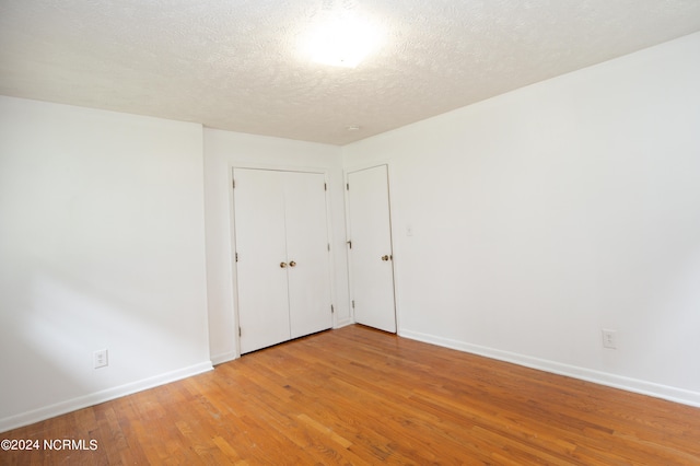 unfurnished room with light wood-type flooring and a textured ceiling