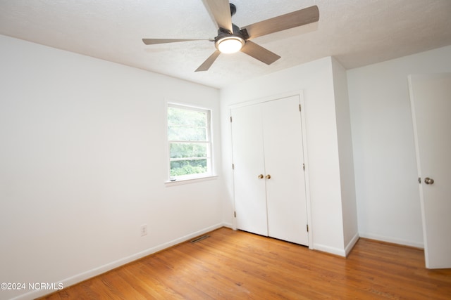 unfurnished bedroom featuring a textured ceiling, light hardwood / wood-style flooring, ceiling fan, and a closet