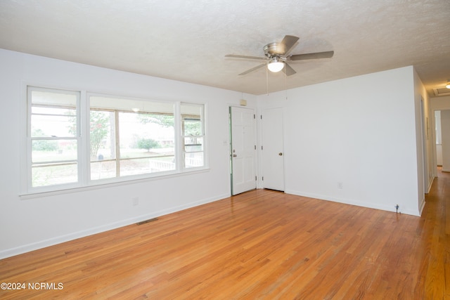 spare room featuring ceiling fan, a textured ceiling, wood-type flooring, and a healthy amount of sunlight