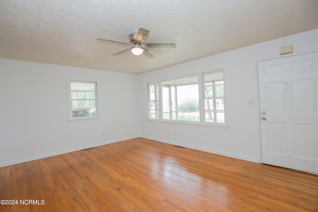 spare room featuring ceiling fan, a wealth of natural light, light hardwood / wood-style floors, and a textured ceiling